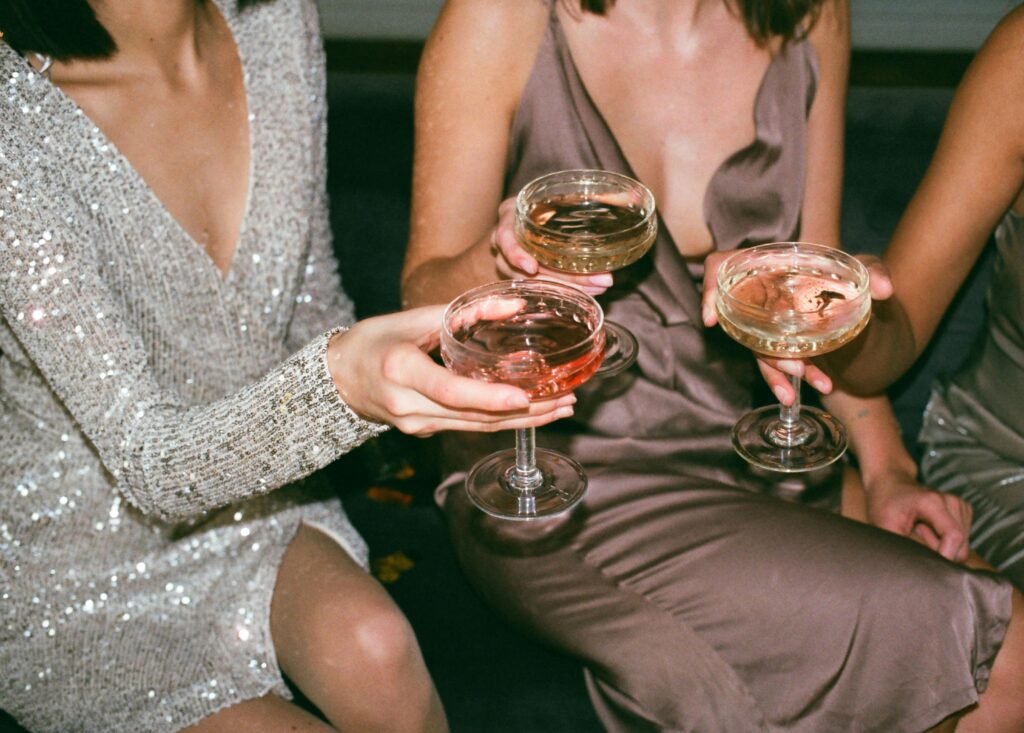 Three women in stylish dresses toasting with champagne at a festive gathering.