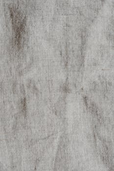 A textured and vintage linen fabric surface with natural wrinkles and neutral tones.