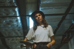 Portrait of a young woman holding a skateboard, exuding a cool and casual vibe.