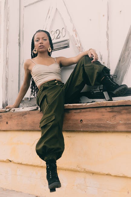 A fashionable woman with braided hair poses in trendy attire outdoors.