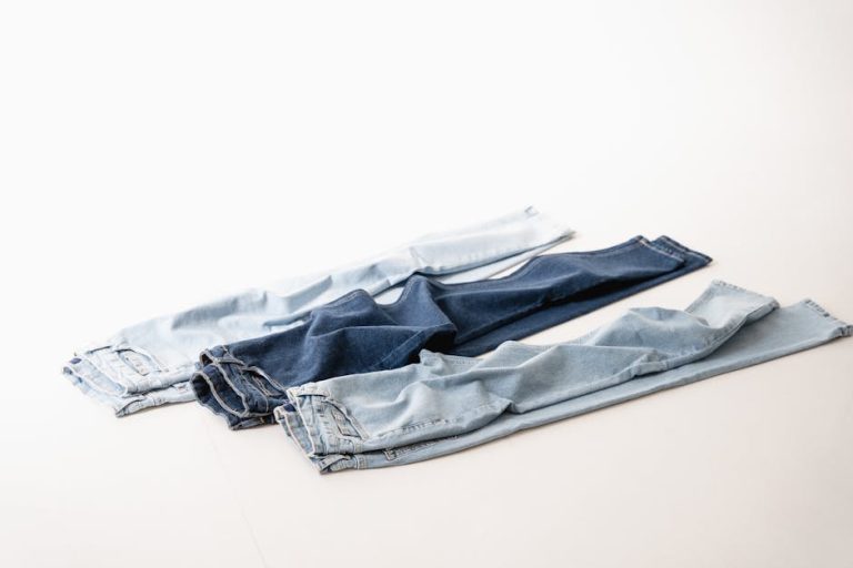 Three pairs of blue jeans arranged on a white background showcasing different denim shades.