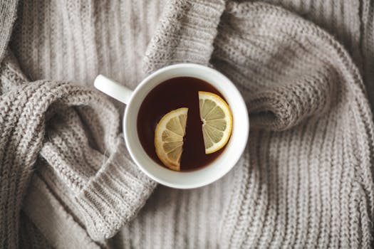 Top view of a warm cup of tea with lemon on a knitted blanket, evoking a cozy and relaxing mood.