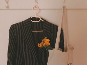 Elegant striped blazer on hanger with vibrant yellow flowers, adding a touch of nature.